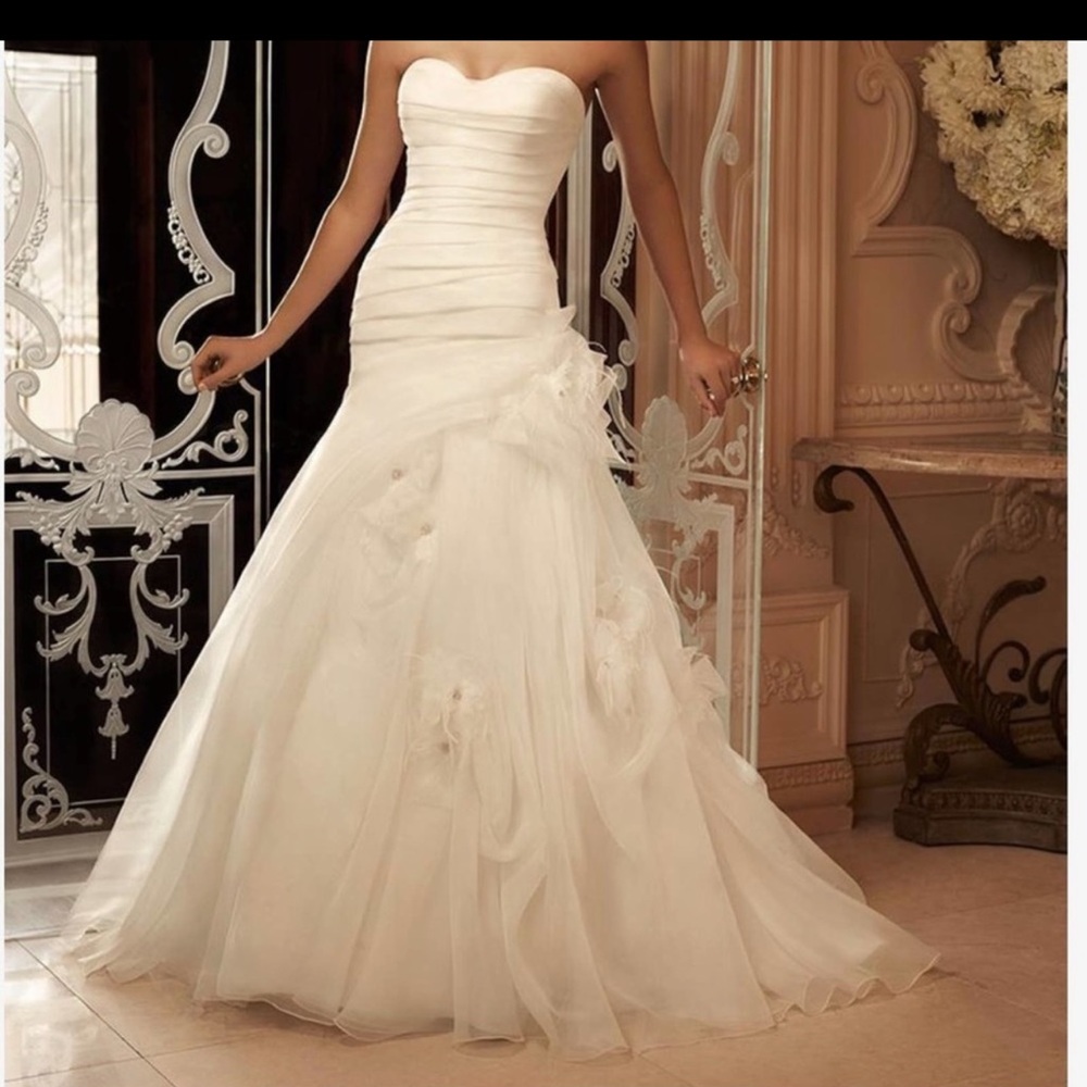 This strapless sweetheart gown has an asymmetrical pleated dropped waist.